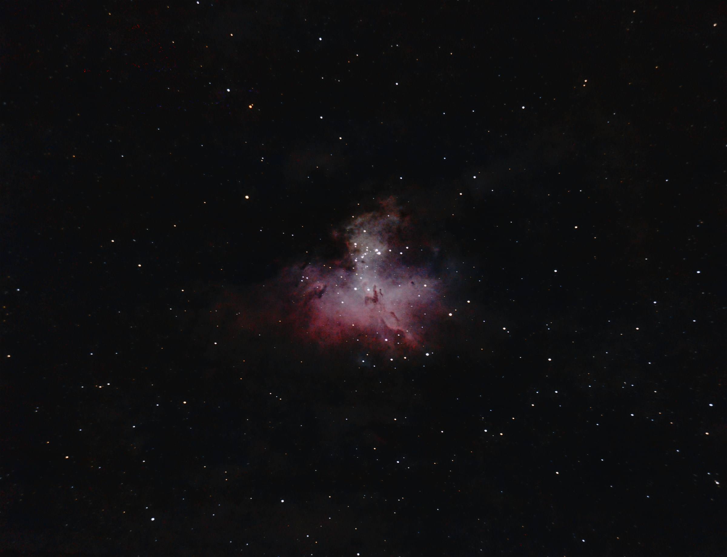 The Eagle Nebula: a red cloud of glowing hydrogen against a dense star field.